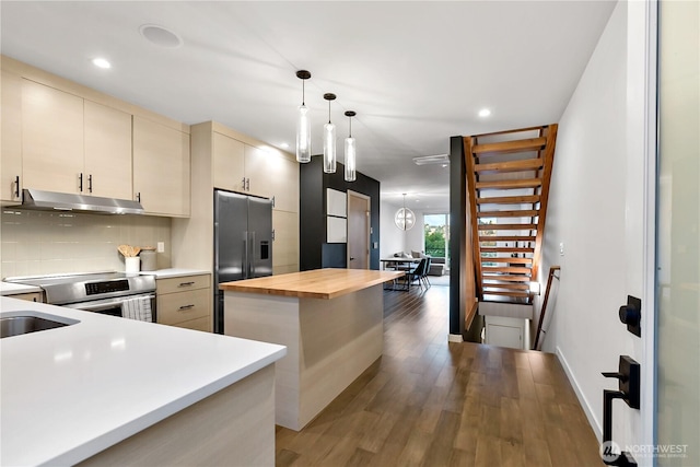 2273 14th Ave W, Seattle, WA 98119 - kitchen with under cabinet range hood, appliances with stainless steel finishes, butcher block counters, cream cabinetry, and light wood-type flooring
