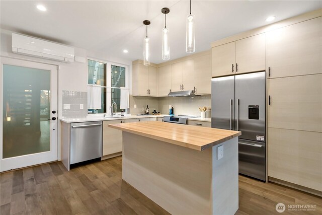 2273 14th Ave W, Seattle, WA 98119 - kitchen featuring stainless steel appliances, a wall unit AC, wood counters, under cabinet range hood, and a sink