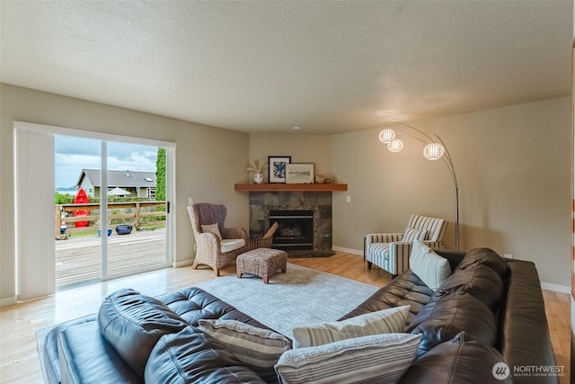 8070 Kispiox Rd, Blaine, WA 98230 - living room with light wood-style floors, a fireplace, baseboards, and a textured ceiling