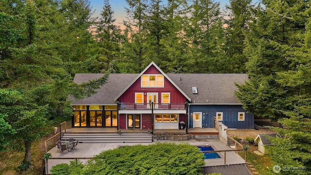 9591 W 34th Cres, Blaine, WA 98230 - back of property at dusk with a balcony, a deck, board and batten siding, and roof with shingles