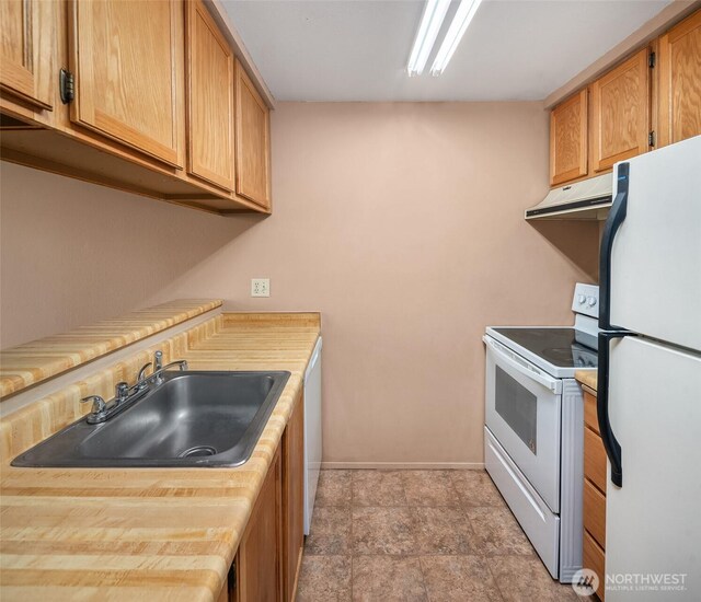 kitchen with white appliances, range hood, a sink, light countertops, and baseboards