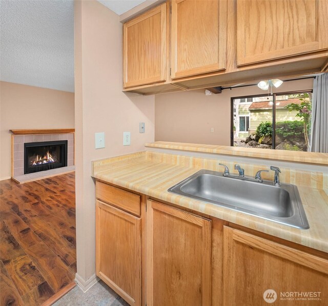 kitchen featuring a sink, light countertops, a fireplace, light brown cabinets, and open floor plan