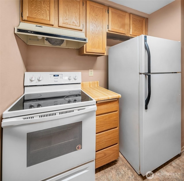kitchen with under cabinet range hood, white appliances, and light countertops
