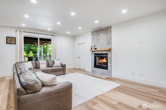 living room featuring a fireplace, recessed lighting, light wood-style flooring, and baseboards