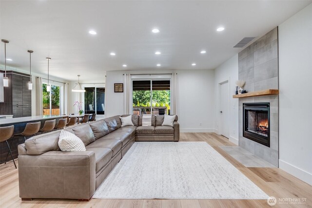 living area featuring recessed lighting, light wood finished floors, a tiled fireplace, and baseboards