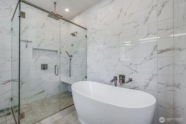 full bathroom with tile walls, a freestanding bath, a marble finish shower, and recessed lighting