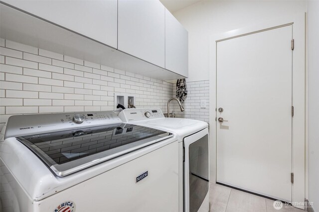 clothes washing area with washer and clothes dryer and cabinet space