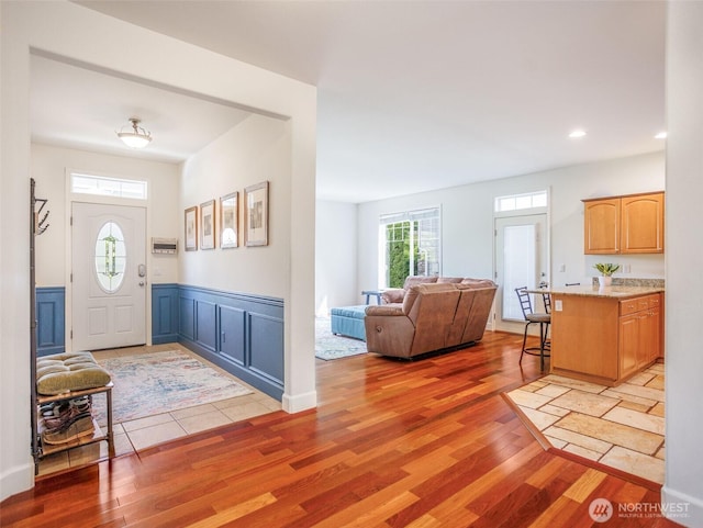 foyer featuring light wood-style flooring, recessed lighting, and a wainscoted wall