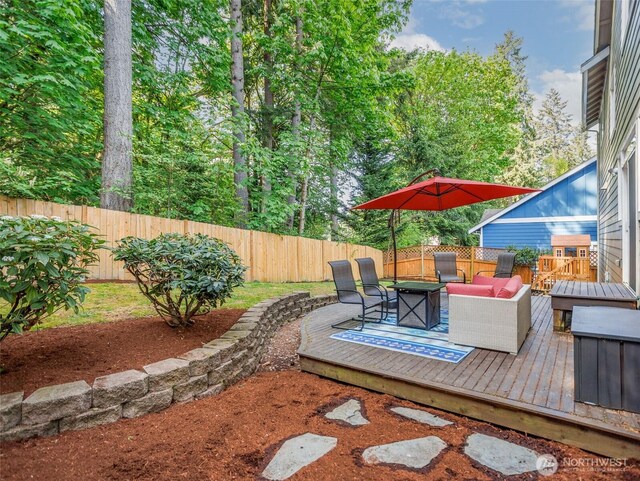 view of patio / terrace with a wooden deck, a fenced backyard, and an outdoor fire pit