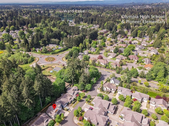 aerial overview of property's location featuring a forest and nearby suburban area