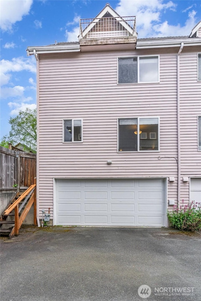view of home's exterior featuring a garage, asphalt driveway, and fence
