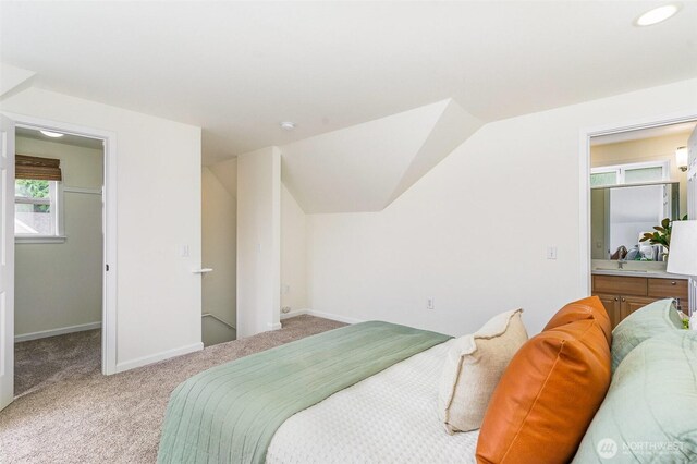 bedroom with light carpet, a spacious closet, baseboards, and vaulted ceiling