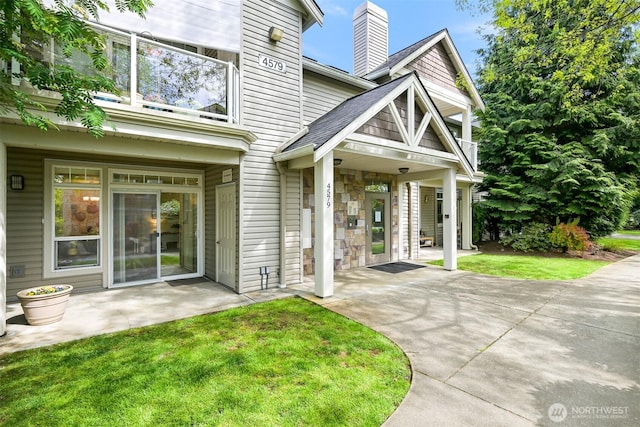 property entrance with a lawn, a chimney, and a patio