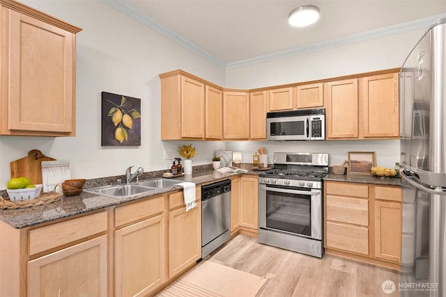 kitchen with appliances with stainless steel finishes, light brown cabinetry, a sink, crown molding, and light wood-style flooring