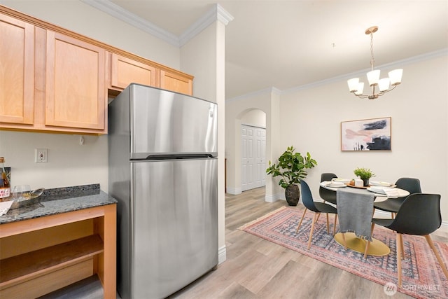 kitchen with freestanding refrigerator, light brown cabinets, crown molding, light wood-style flooring, and arched walkways