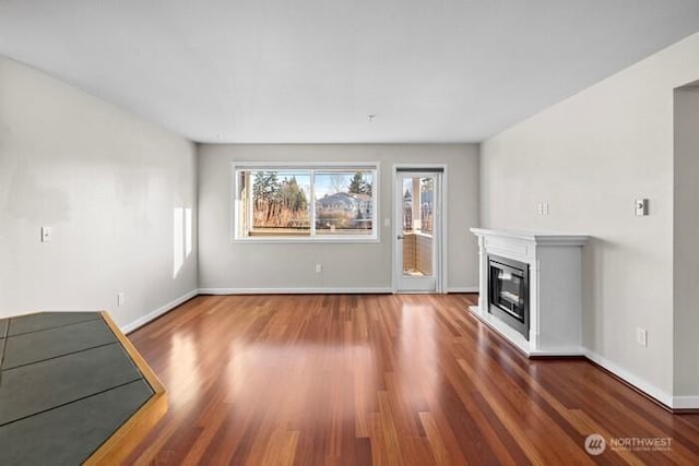 13426 97th Ave E Unit 204, Puyallup, WA 98373 - unfurnished living room with wood finished floors, a glass covered fireplace, and baseboards