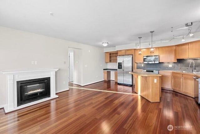 13426 97th Ave E Unit 204, Puyallup, WA 98373 - kitchen with appliances with stainless steel finishes, a sink, a center island, dark wood finished floors, and tasteful backsplash