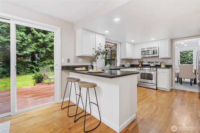 21016 NE 33rd Pl, Sammamish, WA 98074 - kitchen featuring stainless steel appliances, a peninsula, white cabinetry, light wood-style flooring, and plenty of natural light