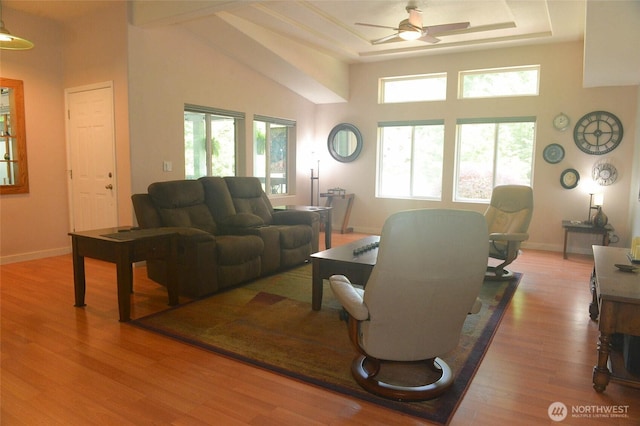 living room featuring ceiling fan, wood finished floors, a towering ceiling, and baseboards