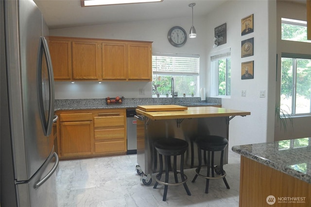 kitchen with freestanding refrigerator, a breakfast bar, lofted ceiling, light marble finish floors, and brown cabinetry