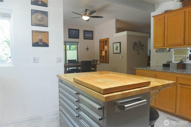 kitchen with butcher block counters, ceiling fan, baseboards, and brown cabinets