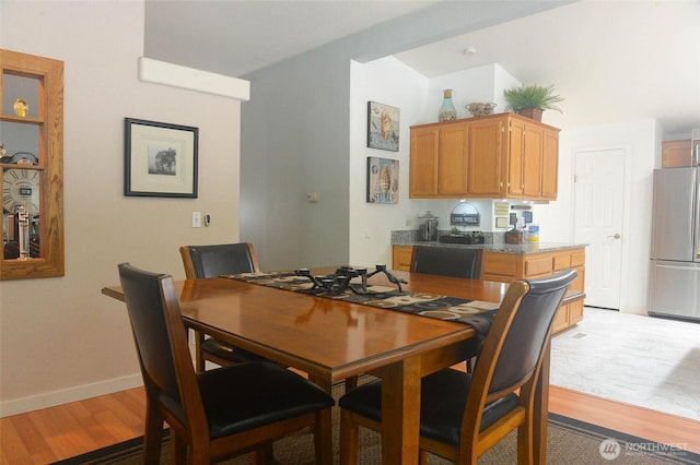 dining area with light wood-type flooring and baseboards