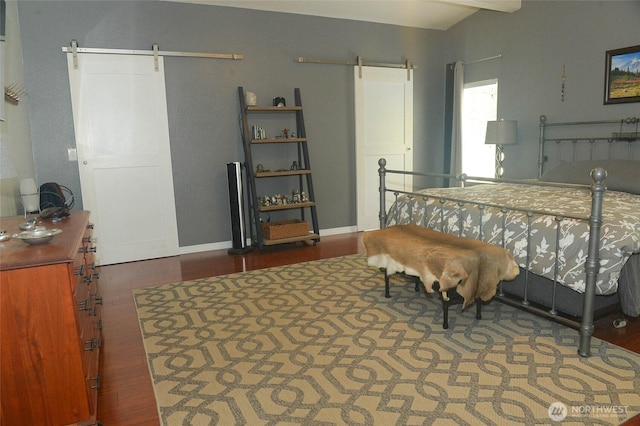 bedroom with a barn door, wood finished floors, and baseboards