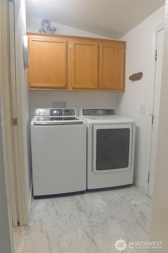 laundry area featuring light marble finish floors, cabinet space, and washer and clothes dryer