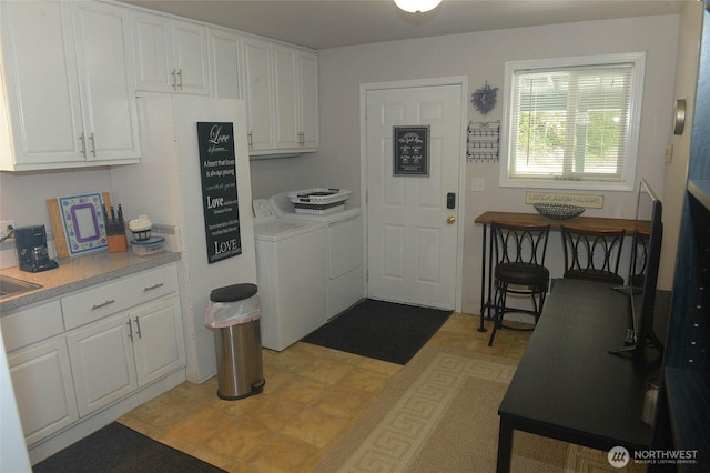 kitchen featuring independent washer and dryer, white cabinetry, and light countertops