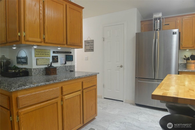332 Rhododendron Dr, Sequim, WA 98382 - kitchen with freestanding refrigerator, light marble finish flooring, brown cabinetry, and dark stone countertops