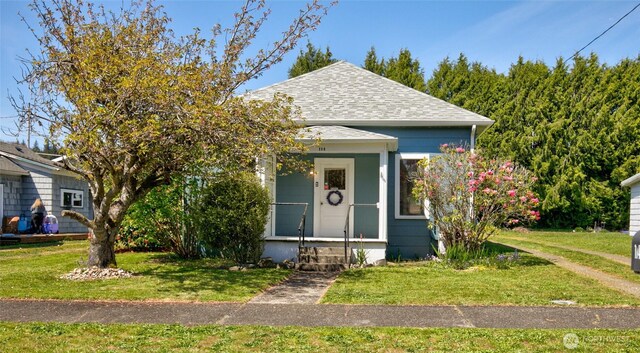 bungalow with a shingled roof and a front lawn