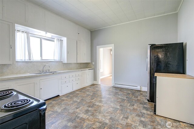 kitchen with a sink, black range with electric cooktop, a baseboard radiator, stone finish flooring, and white cabinets