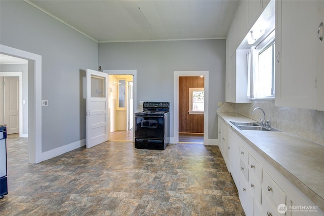 kitchen featuring black range with electric cooktop, a sink, stone finish floors, white cabinetry, and baseboards
