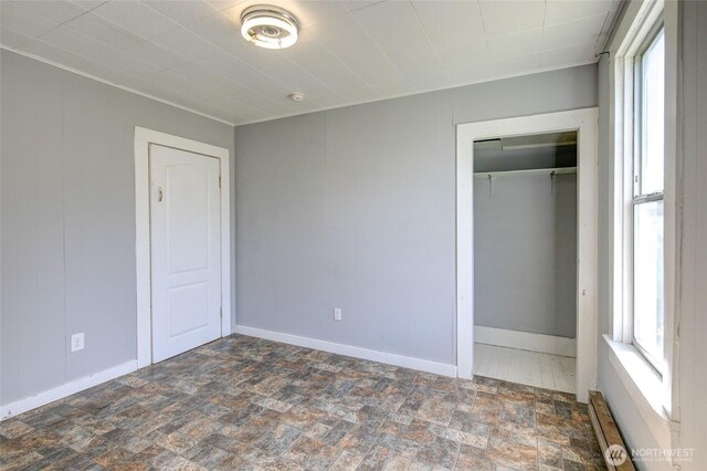 unfurnished bedroom featuring stone finish flooring, a closet, and baseboards