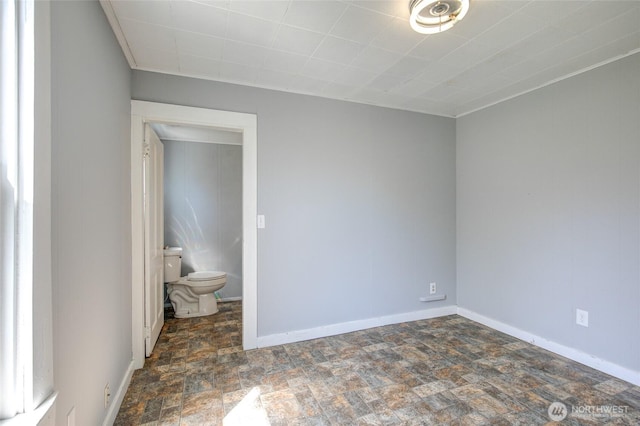 unfurnished room featuring stone finish flooring and baseboards