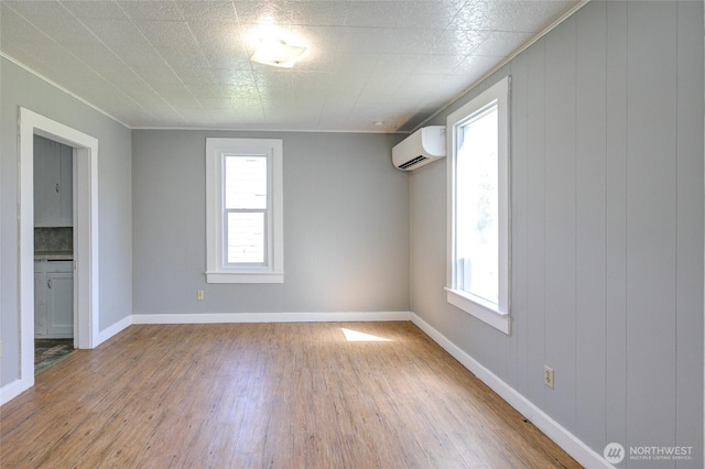 unfurnished room featuring a wall mounted AC, wood finished floors, and baseboards