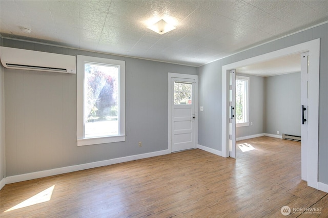 foyer featuring a wall mounted AC, a baseboard heating unit, light wood-type flooring, and baseboards