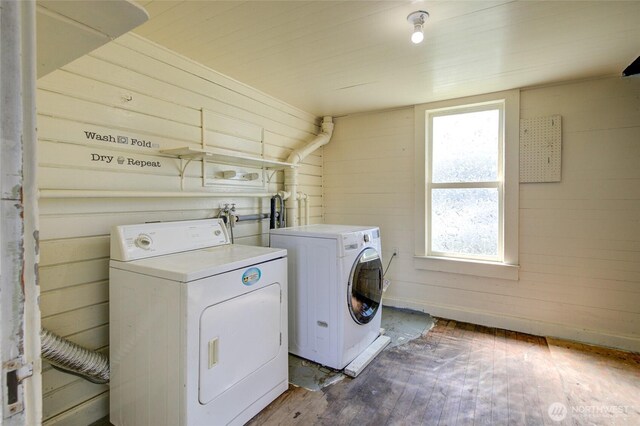 clothes washing area featuring independent washer and dryer, hardwood / wood-style floors, and wooden walls