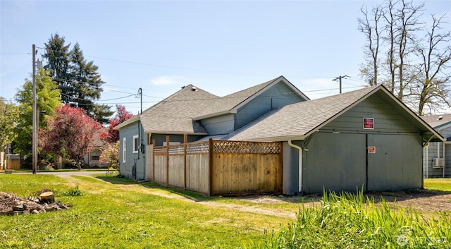 view of side of home with roof with shingles and a lawn