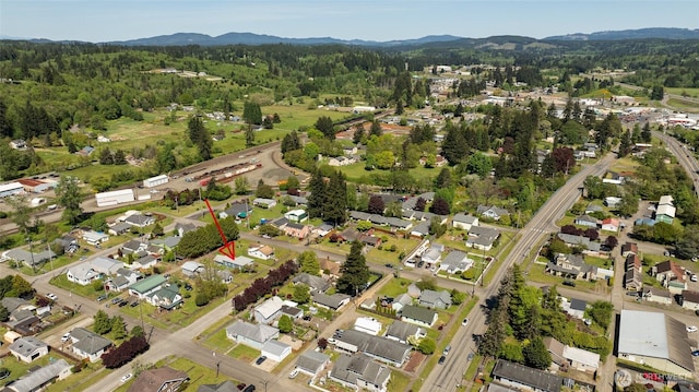 aerial view of property and surrounding area featuring a heavily wooded area and a mountainous background