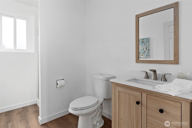 bathroom featuring vanity, wood finished floors, baseboards, and toilet