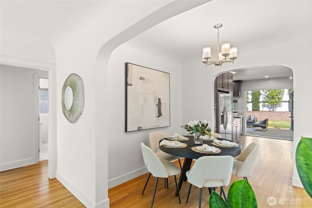 3112 13th Ave S, Seattle, WA 98144 - dining area featuring arched walkways, light wood-type flooring, baseboards, and a chandelier