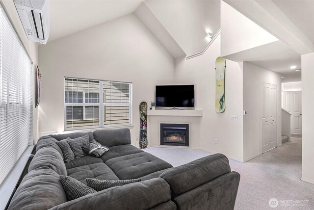 living room featuring light carpet, baseboards, a glass covered fireplace, and high vaulted ceiling