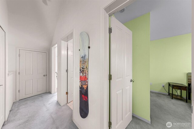 hall featuring light colored carpet and lofted ceiling