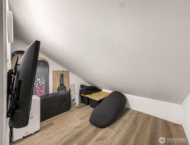 bonus room with light wood-style flooring and vaulted ceiling
