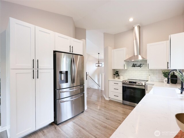 6723 50th Pl NE, Marysville, WA 98270 - kitchen featuring appliances with stainless steel finishes, a sink, wall chimney exhaust hood, white cabinetry, and light wood-style flooring