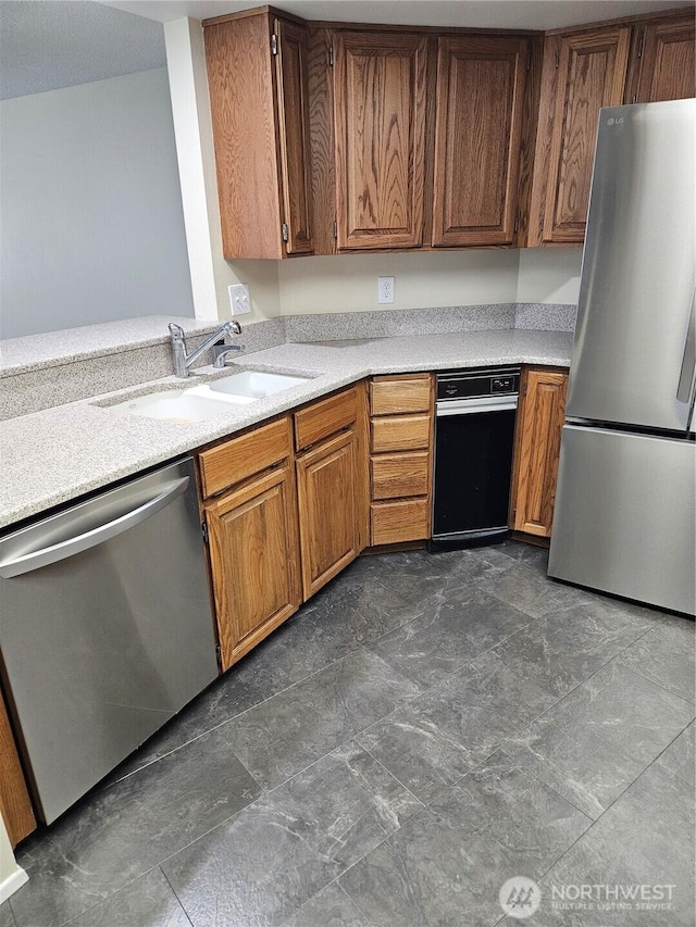 kitchen featuring appliances with stainless steel finishes, a sink, light countertops, and brown cabinets
