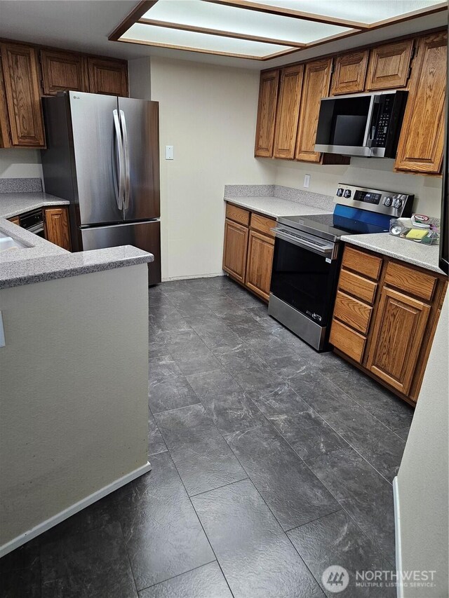 kitchen featuring stainless steel appliances, light countertops, and brown cabinets