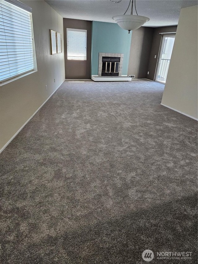 unfurnished living room featuring carpet, a fireplace, and baseboards