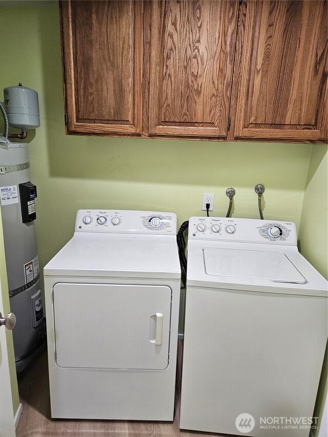 washroom featuring washer and clothes dryer, cabinet space, and secured water heater